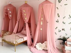 three pink canopy beds in a girls'bedroom