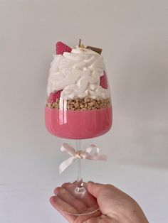 a hand holding a wine glass filled with dessert