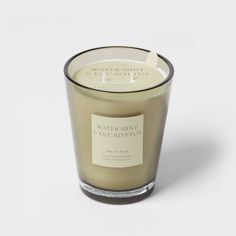 a candle that is sitting on top of a white surface with the words water mint and eucalyptus