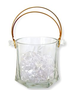 a glass bucket filled with ice on top of a white table next to a wooden handle