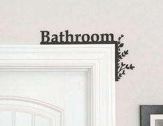 the bathroom sign is hanging on the wall above the door and in front of it are two framed photos