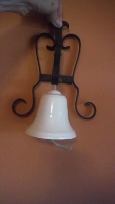 a hand holding a bell on top of a wall