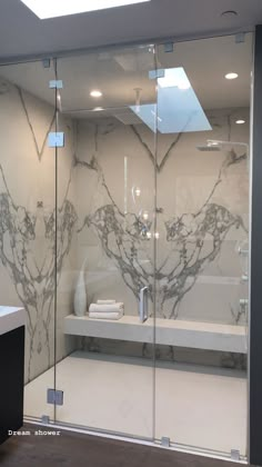 a glass shower door in a bathroom with marbled walls and floor tiles on the wall