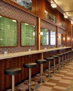 a row of bar stools sitting in front of a wall with pictures on it