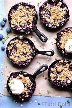 four blueberry crumbles with whipped cream on top