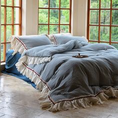 a bed with blue and white bedspread sitting in front of two large windows