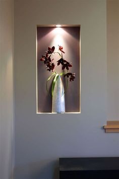 a white vase with red flowers in it sitting on a table next to a fireplace