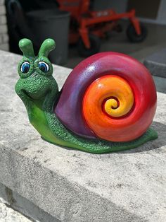 a colorful snail figurine sitting on top of a cement slab