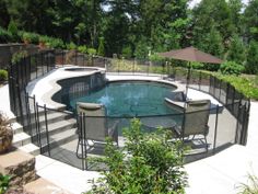 an above ground pool surrounded by fenced in area with chairs and umbrellas around it