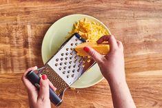 a woman grating cheese on top of a green plate next to a grater