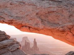 an arch in the side of a mountain with rocks and sand on it's sides