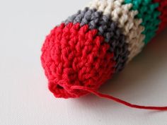 a crocheted red, white and black object sitting on top of a table