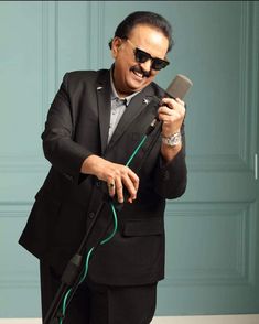 a man in a suit and sunglasses holding a hair dryer