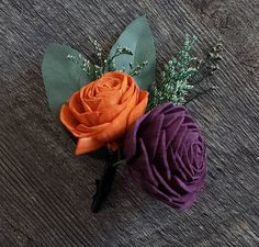 an orange and purple flower sitting on top of a wooden table next to each other