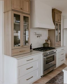 a kitchen with white cabinets and stainless steel stove top oven in the center, surrounded by wood flooring