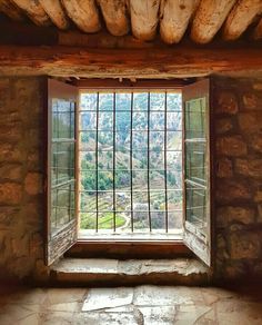 an open window with bars on it in a stone wall and floored area next to the window