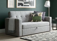 a living room with green walls and grey couch in the center, black and white rug on the floor