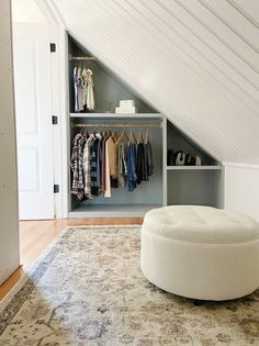 a white ottoman sitting on top of a rug next to a closet filled with clothes