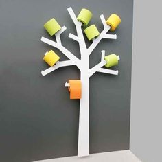 a white tree with yellow and green cups attached to it's branches on a gray wall