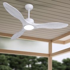 a white ceiling fan mounted on the side of a wooden building with trees in the background