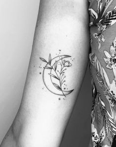 a woman's arm with a flower and crescent tattoo on the left inner arm