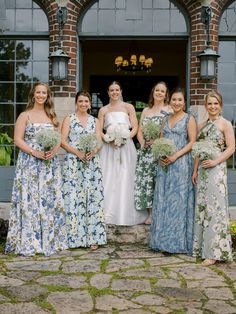 a group of women standing next to each other in front of a building with flowers