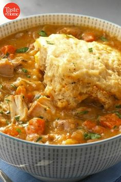 a bowl filled with chicken and vegetable soup on top of a blue napkin next to a fork