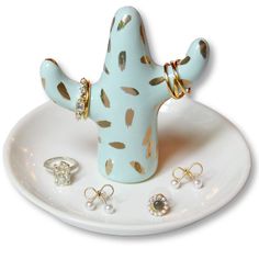 a cactus shaped ring holder on a plate with other rings around it and some diamonds