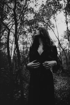 a woman standing in the woods with her hands on her chest