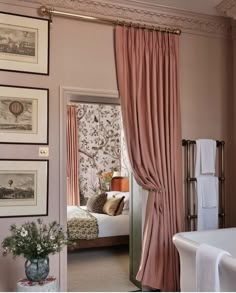 a bedroom with pink walls and pictures hanging on the wall, along with a bathtub