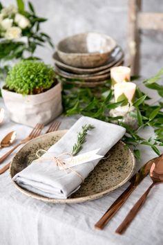 the table is set with silverware and napkins, along with some greenery