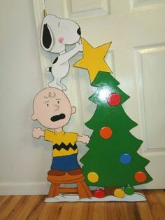 a cardboard charlie brown christmas tree next to a door with a cartoon character on it