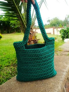 a green crochet tote bag sitting on top of a cement slab with the words how to crochet a tote bag pattern for beginners