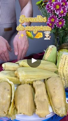 a person cutting corn on the cob with a knife and flowers in the background