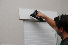 a man is using a drill to fix a window sealer on the side of a wall