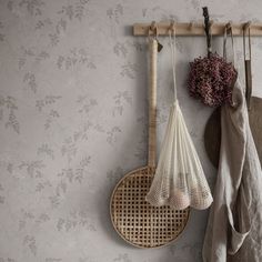 two baskets hanging on a wall next to a wooden rack with umbrellas and flowers