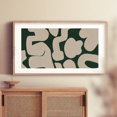 an art print hangs on the wall next to a wooden cabinet with two baskets in front of it