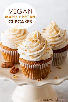 three cupcakes with white frosting and pecans on a cake platter