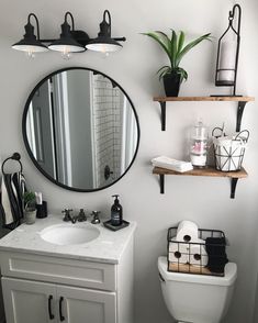 a white toilet sitting under a bathroom mirror next to a sink and shelf filled with items