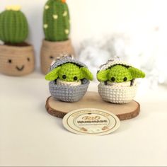 two crocheted baby yoda dolls sitting next to each other on a table