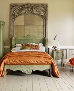 a bedroom with an orange blanket on the bed and white furniture in the room,