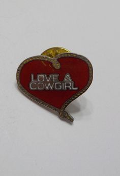 a red and gold heart shaped pin with the words love a cowgirl on it