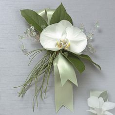 a boutonniere with white flowers and greenery on the side, attached to a wall