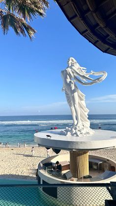 there is a statue on the beach by the water