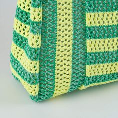 a green and yellow knitted bag on a white surface