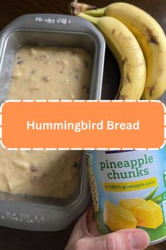 a hand holding a can of hummingbird bread next to some bananas