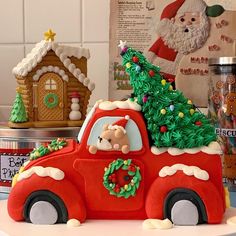 a red truck with a christmas tree on the back and santa's house in the background