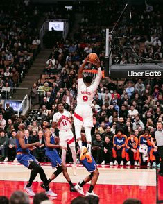 the basketball player is going to dunk the ball in front of the other players