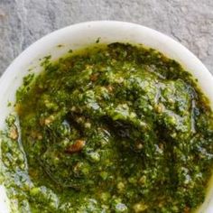 a white bowl filled with pesto on top of a table