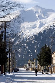 a person walking down a snowy street in front of a mountain